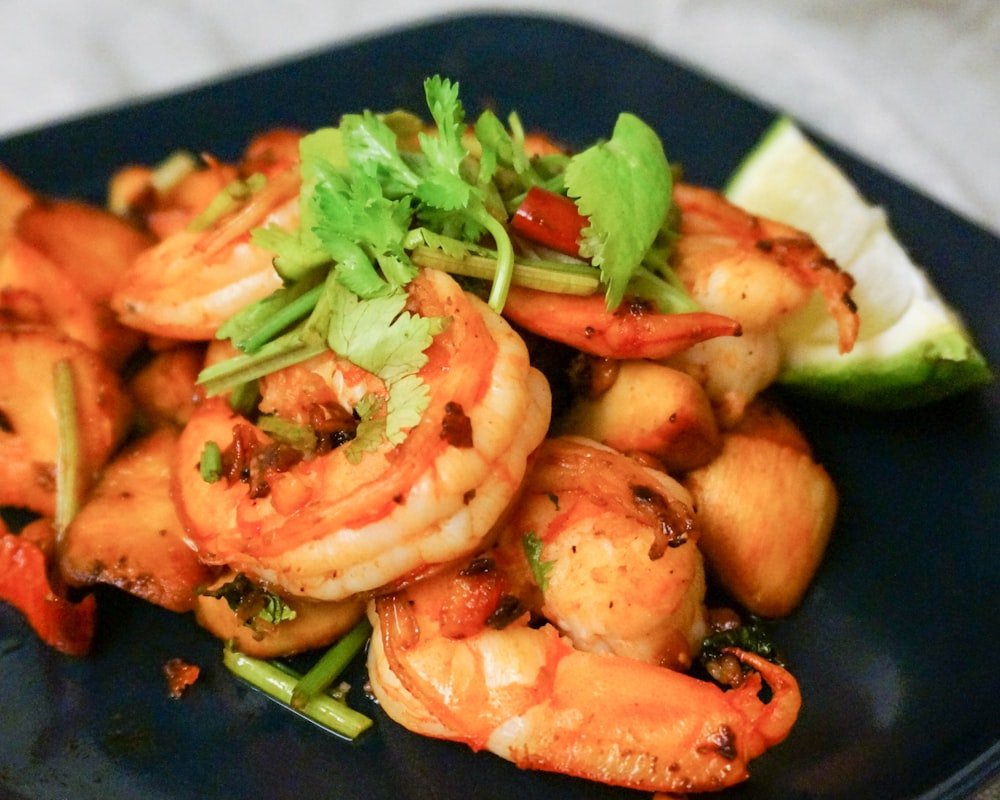 Hanuma's Spicy — prawns and cuttlefish tossed with peanuts, onions and exotic spices on a dark plate.