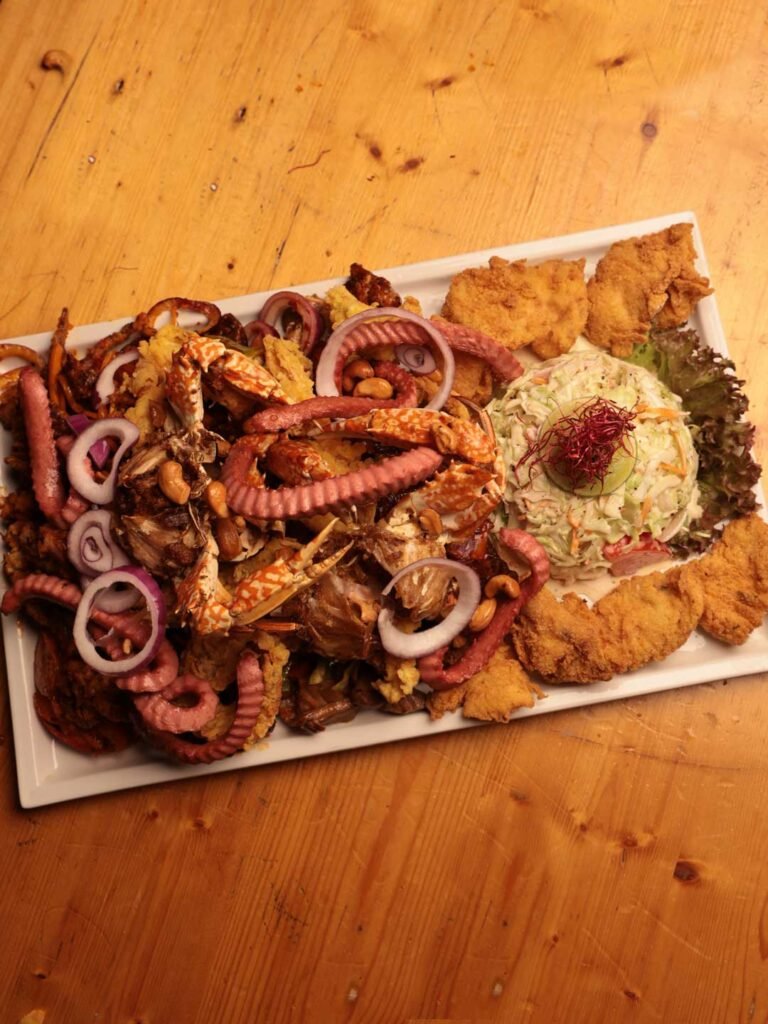 An overhead view of a long table covered in shared plates, with guests reaching in from every side.